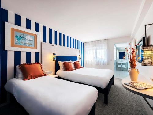 two beds in a room with blue and white stripes at ibis Styles Quiberon Centre in Quiberon