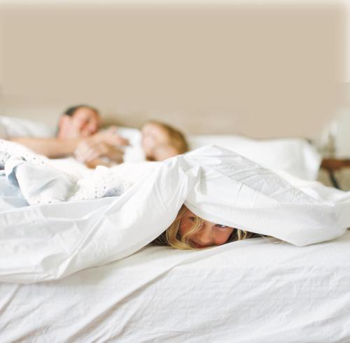 a group of people laying in bed under a blanket at Country Inn & Suites by Radisson, Topeka West, KS in Topeka