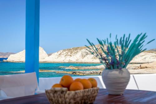 a table with two baskets of oranges and a vase at Esperanza Home Mandrakia in Mandrakia