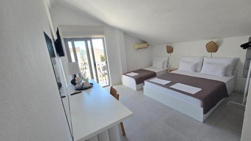 a white room with a bed and a desk and a bed and a window at Vele House Walk to Beach in Herceg-Novi