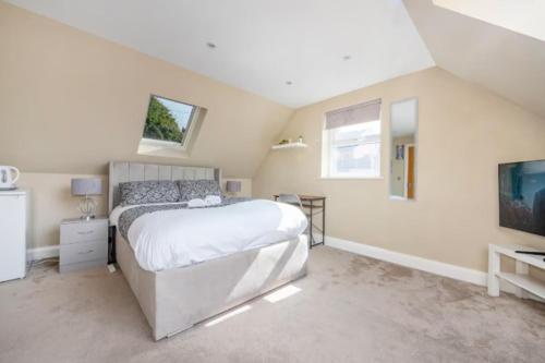 a white bedroom with a bed and a tv at RA7C Stylish Loft Stay in Batley