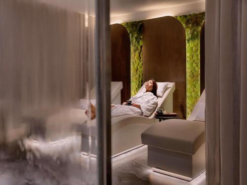a woman laying in a bed in a hotel room at Sofitel Auckland Viaduct Harbour in Auckland