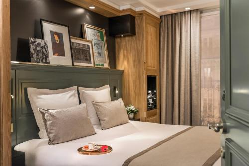 a bedroom with a large white bed with a tray on it at Hotel Ducs de Bourgogne in Paris