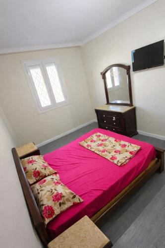 a bedroom with a bed with pink sheets and a dresser at F3 SALAMANDRE à CORNICHE CASA MAZA in Mostaganem