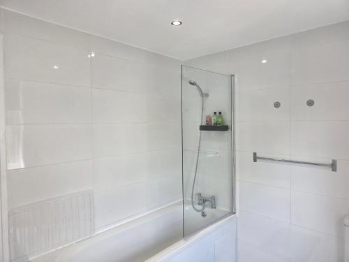 a white bathroom with a shower with a glass door at Charming Wootton in Hail Weston