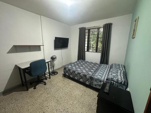 a bedroom with a bed and a desk and a window at Habita Coliving La Palma in Medellín