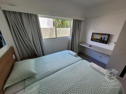 a small bedroom with a bed and a window at Vila Sol Serrambi in Porto De Galinhas