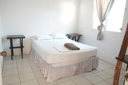 a bed in a white room with a white floor at Mojo Surf House in Popoyo