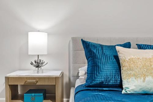 a bed with blue pillows and a table with a lamp at Spacious 2BR N Gulch Walk to Broadway & Rooftops in Nashville