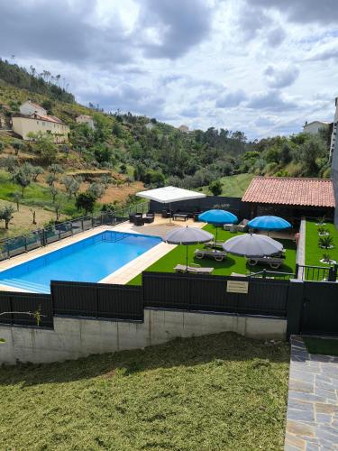 a swimming pool with umbrellas and tables and chairs at Casa Resineiro com Piscina, Garagem e Terraço in Proença-a-Nova