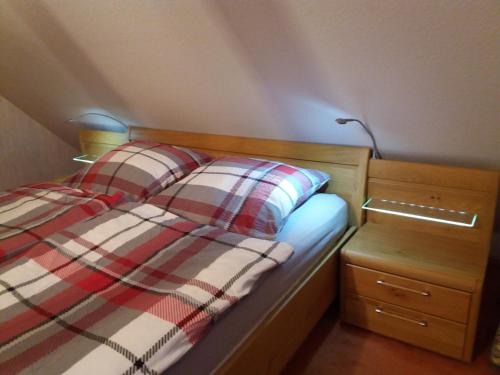 a bed with a plaid blanket and a night stand at Ferienwohnung Bandow in Woltersdorf