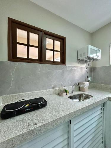 a kitchen counter with a sink and a microwave at Búzios Apartamento Charmoso in Búzios