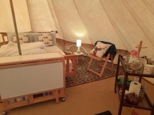 a room with a tent with a couch and a chair at Glamping Bell Tent in Norton Saint Philip