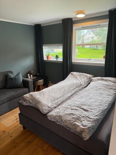 ein Bett in einem Schlafzimmer mit Fenster und eine Couch in der Unterkunft LeiraLy in Veblungsnes