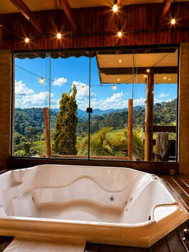 a bath tub in a room with a large window at Refugio nas Alturas LANDIN & CHARM in Santo Antônio do Pinhal
