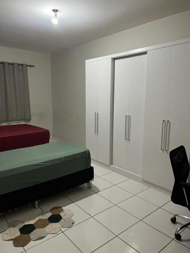 a bedroom with a bed and white cabinets and a chair at Quarto família ap5 in Montes Claros