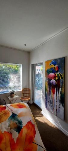 a bedroom with a bed and a painting of people with umbrellas at Anyomi Zen in Gqeberha