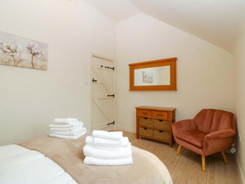 a bedroom with a bed and a chair and towels at No 2 The Stables in Llangefni