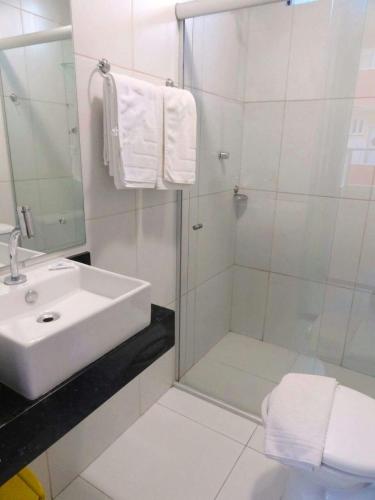 a white bathroom with a sink and a shower at Pousada Panorâmica in Aracaju