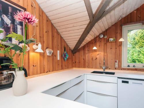 a kitchen with wooden walls and a vase with flowers at 6 person holiday home in Oksbøl in Oksbøl