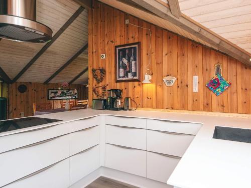 a kitchen with white cabinets and a wooden wall at 6 person holiday home in Oksbøl in Oksbøl