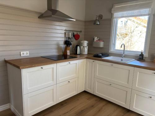 a kitchen with white cabinets and a sink and a window at Villa Emma in Alsterbro