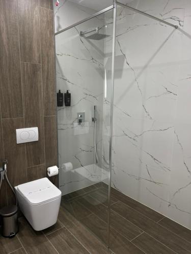a bathroom with a glass shower and a toilet at AMAD Aparthotel in Sarandë