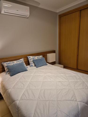 a bedroom with a large white bed with blue pillows at CARAVELL ARMAÇÃO de PÊRA in Armação de Pêra