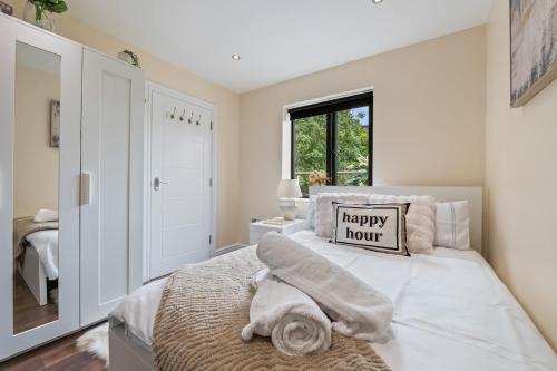 a bedroom with a happy hour pillow on a bed at Premium Apartment Steps from Wembley Park in London