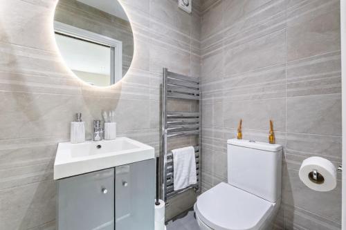 a bathroom with a toilet and a sink and a mirror at Premium Apartment Steps from Wembley Park in London