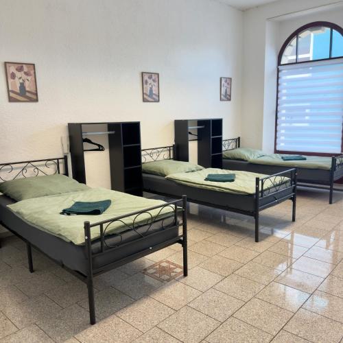a room with three beds and a window at Central Apartments Hof in Hof