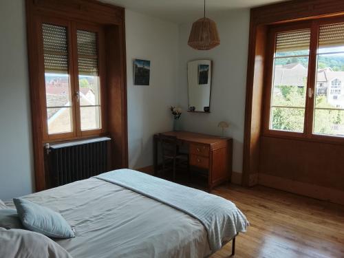 a bedroom with a bed and a dresser and windows at VILLA Douce Loue in Ornans