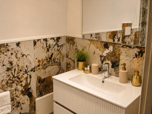a bathroom with a sink and a marble wall at Da Mario in Guarene