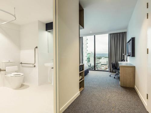 a bathroom with a toilet and a desk and a window at ibis Adelaide in Adelaide