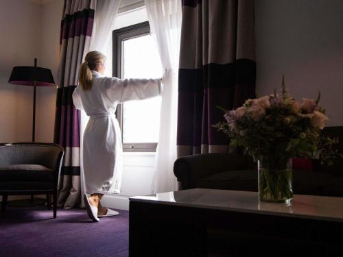a woman is looking out of a window at Sofitel Buenos Aires Recoleta in Buenos Aires