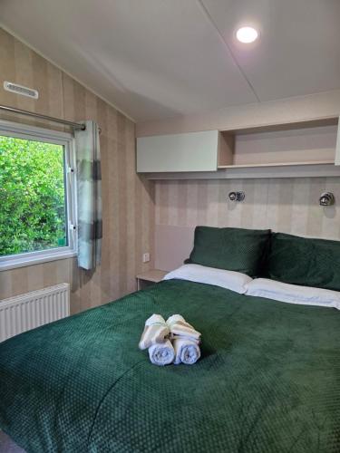 a bedroom with a large green bed with towels on it at 2 bedrooms caravan with a sea view in Poole