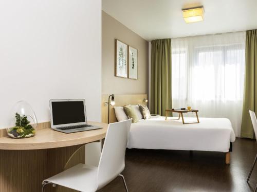 a hotel room with a bed and a desk with a laptop at Aparthotel Adagio Access Paris Reuilly in Paris