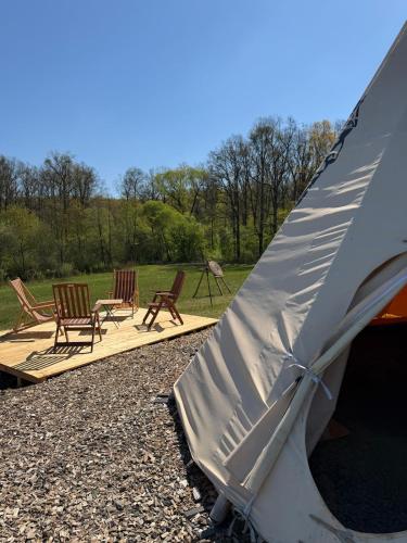 a group of chairs sitting next to a tent at Teepee u Vlčího potoka in Jičíněves