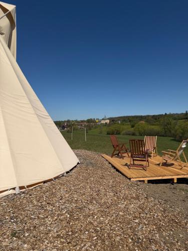 a group of chairs and a tent on a beach at Teepee u Vlčího potoka in Jičíněves