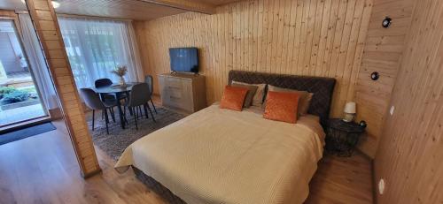 a bedroom with a bed and a table and a television at Sodyba pas Babą - Apartamentai SMILGIJA Šventoji in Palanga
