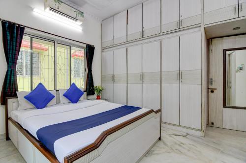 a bedroom with a large bed with blue pillows at Hotel Elguse in kolkata