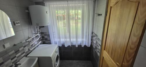 a bathroom with a washing machine and a window at Sodyba pas Babą - Apartamentai SMILGIJA Šventoji in Palanga