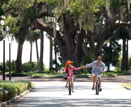 a man and a little girl riding bikes and holding hands at Montage Palmetto Bluff in Bluffton