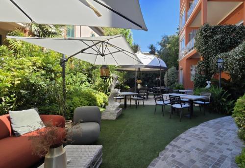 a patio with tables and chairs and an umbrella at Hotel Viscardo in Forte dei Marmi