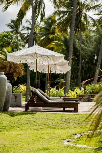 a beach chair with an umbrella in a park at Villa Cote Sud Pousada De Charme - Pé na Areia in São Miguel dos Milagres