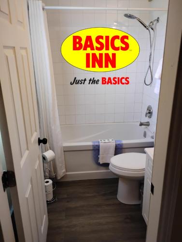 a bathroom with a toilet and a sign that reads basins inn just the basics at BASICS Inn in Truro