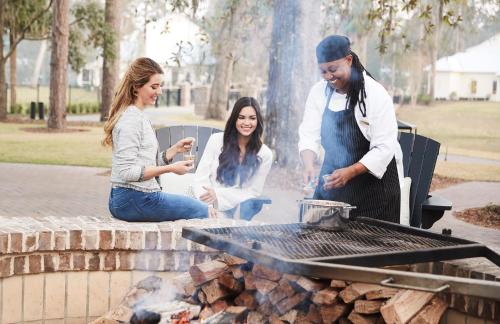 a man and two women cooking on a grill at Montage Palmetto Bluff in Bluffton