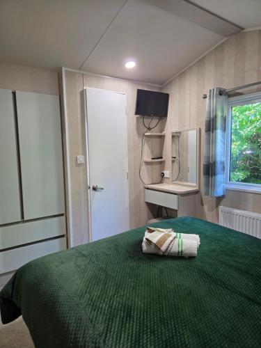 a bedroom with a bed with a green blanket and a window at 2 bedrooms caravan with a sea view in Poole