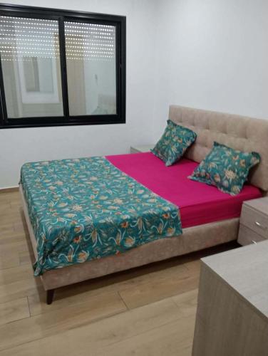 a bedroom with a large bed with a redspread and pillows at Un Studio haut standing à Monastir in Monastir