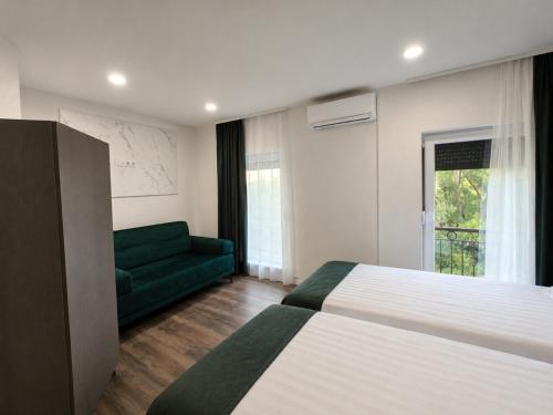 a bedroom with a bed and a green couch at Apartments and Rooms Villa Majestic in Bihać